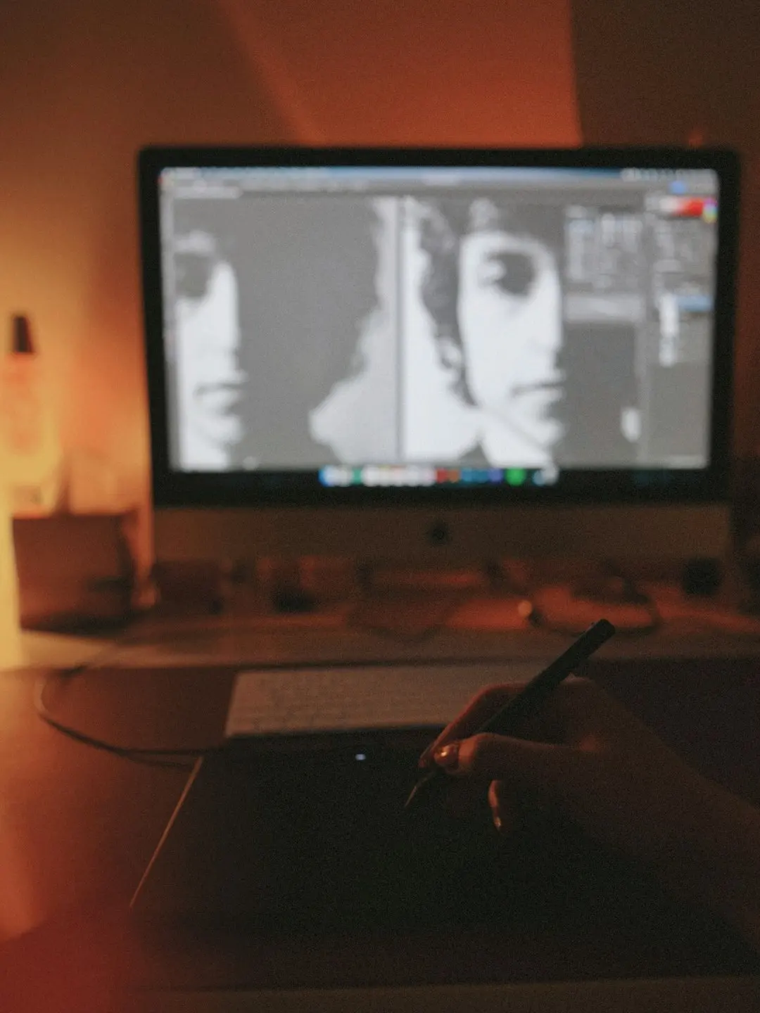 Person using a stylus on a drawing tablet in front of a computer.